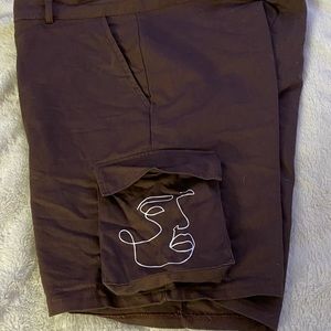 Brown cargo shorts with a face drawing on the side pocket
